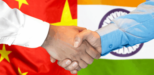 immagine di 2 mani strette con dietro le bandiere della cina e dell'india