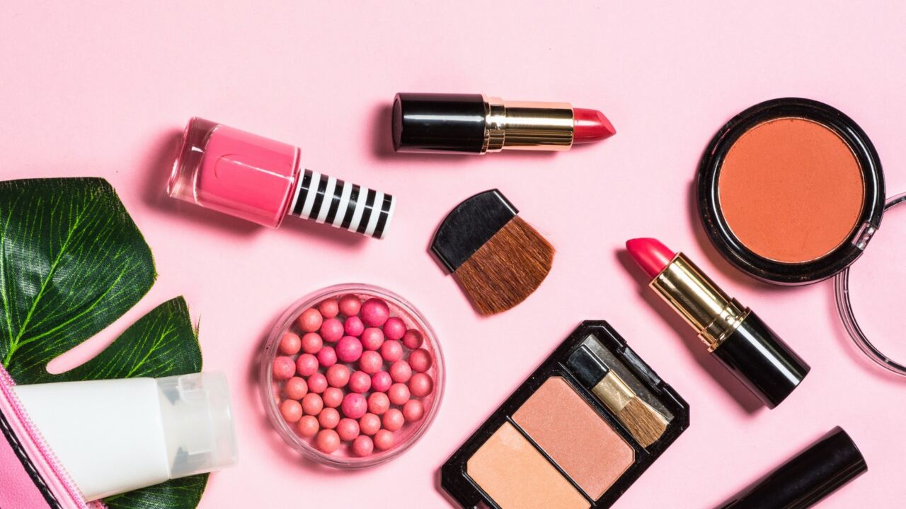 makeup such as nail polish, lipsticks, blush, and more on a pink background